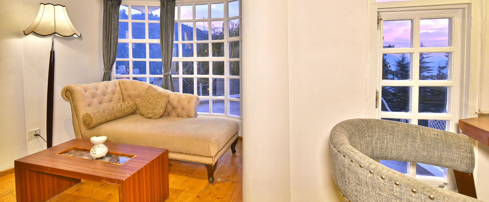 Spacious suite at DLS Hillcrest Resort, Shimla, featuring a living area with a sofa and large windows offering scenic views.